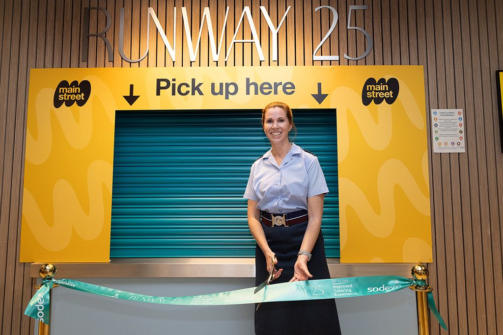 Group Captain Louise Henton, Station Commander of Royal Air Force Brize Norton, smiles as she cuts a ceremonial ribbon, thus officially opening the Runway 25 food pick-up counter.
